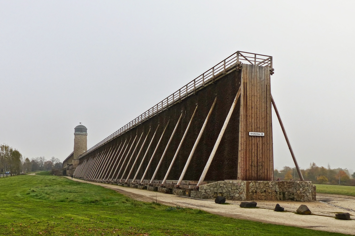 . Bad Nauheim (Wetterau) - Die Gradierbauten IV/V, die sogenannte Lange Wand mit dem Windm�hlenturm. 01.11.2014 (Jeanny) 

Ein Gradierwerk ist eine Anlage zur Salzgewinnung. Sie besteht aus einem Holzger�st, das mit Reisigb�ndeln (vorwiegend Schwarzdorn) verf�llt ist. Das Verb  gradieren  bedeutet  einen Stoff in einem Medium konzentrieren . Im Falle eines Gradierwerks wird der Salzgehalt im Wasser erh�ht, indem Sole durch das Reisig hindurchgeleitet wird, wobei auf nat�rliche Weise Wasser verdunstet. Au�erdem lagern sich Verunreinigungen der Sole an den Dornen ab; dadurch wird die Qualit�t des erzeugten Salzes erh�ht.
