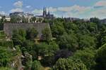 Blick über das grüne Petrustal auf die Oberstadt von Luxemburg mit der Kathedrale Notre Dame und dem Monument der „Gëlle Fra“ auf der Place de la Constitution.
